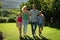 Happy caucasian couple with daughter and son outdoors, walking in sunny garden