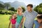 Happy caucasian couple with daughter and son outdoors, walking in sunny garden