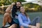 Happy caucasian couple sitting on outdoor tennis court by net recovering after playing tennis