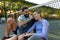 Happy caucasian couple sitting on outdoor tennis court by net recovering after playing tennis