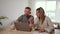 happy caucasian couple sitting at table engaging in business using laptop