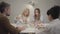 Happy Caucasian family gathered at the table, drinking tea and chatting. Mature blond woman pouring hot drink into cups