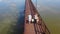 Happy caucasian family holding hands walking wooden bridge over lake water