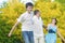 Happy Caucasian Family of Three Having Fun Together and Running in Summer Forest With Joined Hands