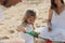 Happy caucasian family in white dress, mother and dad playing with little girl with sand toys playing in sandbox at