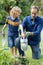 Happy caucasian father in garden with son, watering plants and gardening together