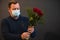 Happy caucasian florist with mask making bouquets of red roses for valentines day delivery