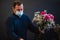 Happy caucasian florist with mask making bouquets of red roses for valentines day delivery