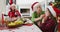 Happy caucasian grandmother wiping her granddaughter mouth at christmas table