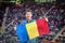 Happy caucasian man holding Romanian national flag in hands at international sport event â€“ supporter at stadium cheering