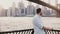 Happy Caucasian man stands near river embankment fence at Brooklyn Bridge scenery, reflecting and enjoying New York view