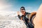 Happy caucasian man taking a selfie hiking a mountain full of snow at winter. Portrait of a skier at vacation