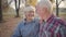 Happy Caucasian mature family looking at each other and smiling. Senior European couple standing in sunlight in autumn