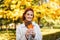 Happy caucasian millennial redhead female in raincoat hold yellow leaf in hands, enjoy freedom