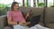 Happy caucasian pregnant woman sitting on sofa and using smartphone and laptop