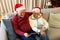 Happy caucasian senior couple having christmas tablet video call embracing at home