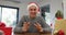 Happy caucasian senior man wearing santa hat making video call at home, talking