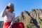 Happy caucasian woman laughing in a phone call in a journey at the mountain. Solo lady traveler, sitting speaking in the telephone