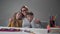 Happy Caucasian woman posing with her smart children sitting at the table. Beautiful young mother hugging her daughter