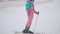 Happy Caucasian woman standing on skis with ski poles looking around and smiling. Camera moves up in slow motion, joyful