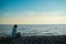 Happy caucasian woman working on a laptop while sitting on a pebble beach.