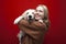 Happy cheerful beautiful girl holding a dog on a red background, a woman hugs a golden retriever puppy and smiles, people with