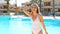 Happy cheerful beautiful girl in white swimsuit hand on head have fun next to swimming pool in summer vacation in resort hotel