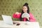 Happy cheerful beautiful young businesswoman with black dreadlocks hairstyle in pink blouse is sitting, holding many dollars,