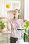 happy and cheerful caucasian woman in a t-shirt in her kitchen makes a green smoothie