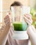 happy and cheerful caucasian woman in a t-shirt in her kitchen makes a green smoothie