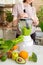 happy and cheerful caucasian woman in a t-shirt in her kitchen makes a green smoothie