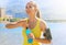 Happy cheerful female athlete with armband for smart phone open power drink bottle after daily training and looking away outdoors