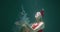 Happy cheerful fun smiling young fairy woman opening hands with Christmas presents floating up underwater slow motion.