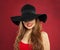 Happy cheerful model woman in black hat on red background. Smiling girl portrait