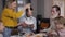 Happy cheerful mother putting spaghetti on grandfather`s plate during family dinner