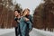 Happy cheerful smiling couple of young people in denim suits in snowy forest in winter on the road . place for text