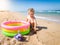 Happy cheerful toodler boy digigng sand on beach and playing with inflatable swimming pool. Child relaxing and having