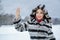 Happy cheerful woman with bright makeup dressed in striped grey and black fur coat waving