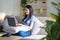 Happy cheerful young asian woman sitting on sofa with laptop, smart beautiful young asian woman chilling in house with