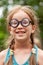 Happy cheerful young little school age girl, one single child in quirky funny big silly glasses smiling laughing, vertical
