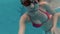 Happy cheerful young woman in red swimming suite in swimming pool, underwater view. Action camera