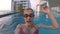 Happy cheerful young woman in red swimming suite in swimming pool, waving a hand. Action camera