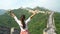 Happy cheering tourist woman at Great Wall of China having fun arms outstretched