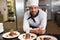 Happy chef looking at camera behind counter of desserts