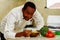 Happy chef wearing white clothes preparing bowl of food in professional kitchen, smiling while finishing last touch