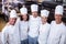 Happy chefs team standing together in commercial kitchen