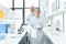 Happy chemists in white coats standing in chemical laboratory with microscopes and flasks