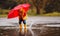 happy child baby boy with rubber boots and umbrella jump in puddle on autumn walk