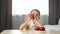 A happy child bites off a slice of a red apple and gives the sign a thumbs up. The concept of healthy food for children