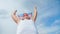 Happy child boy in big red funny glasses raising hand having positive emotion at blue sky background